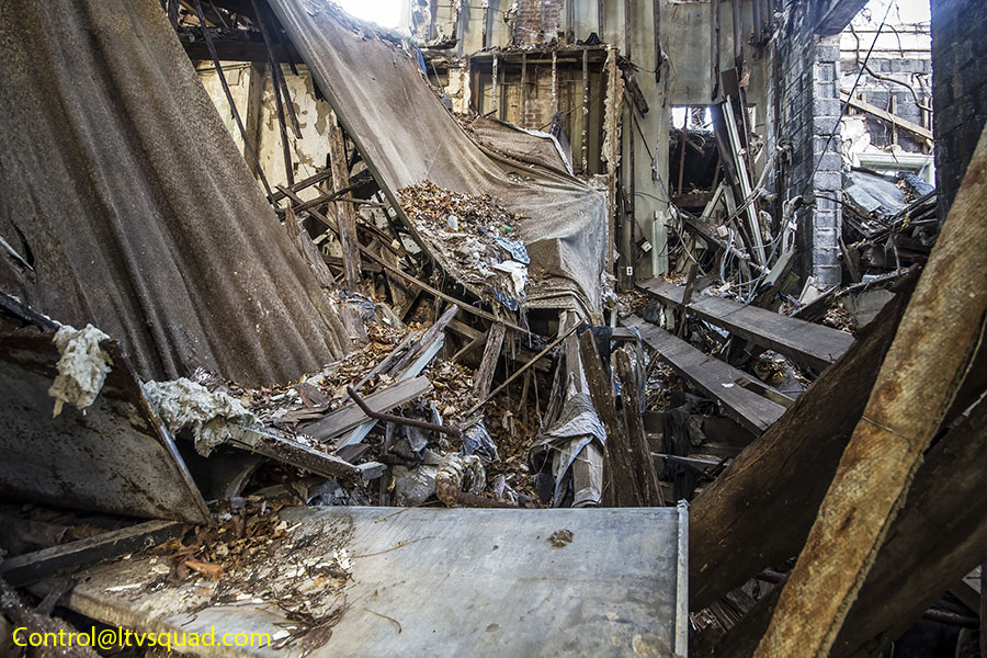Inside, the support beams have collapsed and the gray, molded carpeting hangs from what remains. 